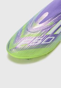 Scarpa da calcio vibrante in gradiente di viola e verde, con un design elegante, superficie testurizzata e un marchio ben visibile sul lato.
