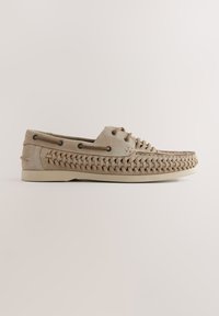 Chaussures à lacets en daim beige avec des détails tissés sur les côtés et des semelles en caoutchouc. Œillets métalliques et accents cousus renforcent le design.