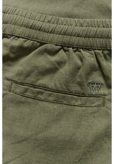 Pantaloni scurți din in de culoare verde măsliniu cu un brâu elastic, dotati cu un buzunar pe spate și logo-ul brodat "W" într-o nuanță subtilă. Detalii texturate vizibile în material.