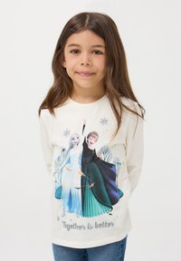 Maglietta a maniche lunghe color crema con personaggi dei cartoni animati in un paesaggio innevato. Il testo stampato sotto dice "Insieme è meglio." Materiale in cotone morbido.