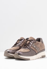 Bruna sneakers med metalliska detaljer, mocka och texturerat läder. Har en kilklack och dekorativa nitar på sidan.