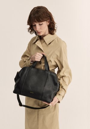 Borsa a mano in pelle nera con finiture dorate, chiusura zip e doppi manici. Presenta una superficie testurizzata e una tracolla staccabile.