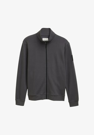 Veste zippée gris foncé avec un col haut, des manches longues, des poignets côtelés et une texture douce. Présente une écusson sur la manche gauche.