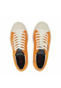 Pomarańczowe i kremowe płócienne trampki z białymi sznurowadłami, gumową podeszwą oraz czarno-białymi metkami z logo na wkładkach i bokach.