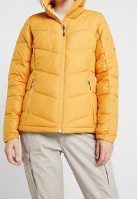 Giacca a vento gialla con zip frontale e cappuccio. Caratterizzata da un design trapuntato, polsini elastici e due tasche laterali.