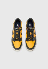 Nike-Sneaker mit schwarzem Ledergrund und leuchtend orangefarbenen Einsätzen. Verfügt über Belüftungsöffnungen, schwarze Schnürsenkel und ein navyblaues Innenfutter.