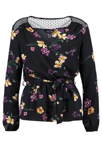 Haut portefeuille noir à fleurs avec manches longues, présentant des fleurs jaunes et violettes, une taille ceinturée et un détail de décolleté transparent à pois.