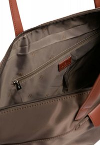 Borsa tote in tessuto marrone con manici in pelle marrone, dotata di una tasca interna con zip e fodera beige con un motivo logo ripetuto.