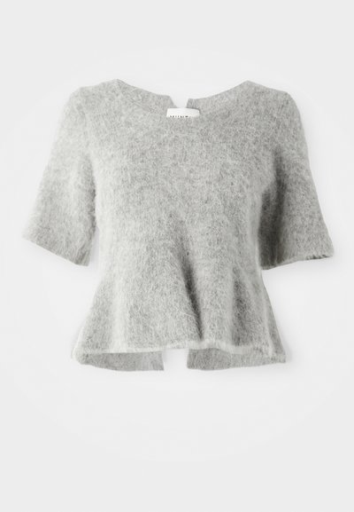 Īsām piedurknēm, brīvi pieguļošs tops, izgatavots no maiga, gaiši pelēka pūkaina materiāla ar noapaļotu apkakli un nedaudz izplešanos apakšmalā.