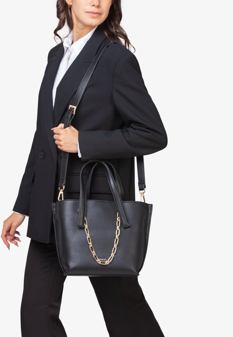 Sort læder tote bag med dobbelte top håndtag, guld kædeaccent og en aftagelig skulderrem. Glat tekstur og struktureret design.