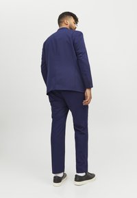 Marineblå dress med skreddersydd passform, enkelt ventilert bak, kombinert med svarte sneakers. Glatt stoff, enkelt design, rene linjer og subtile detaljer.