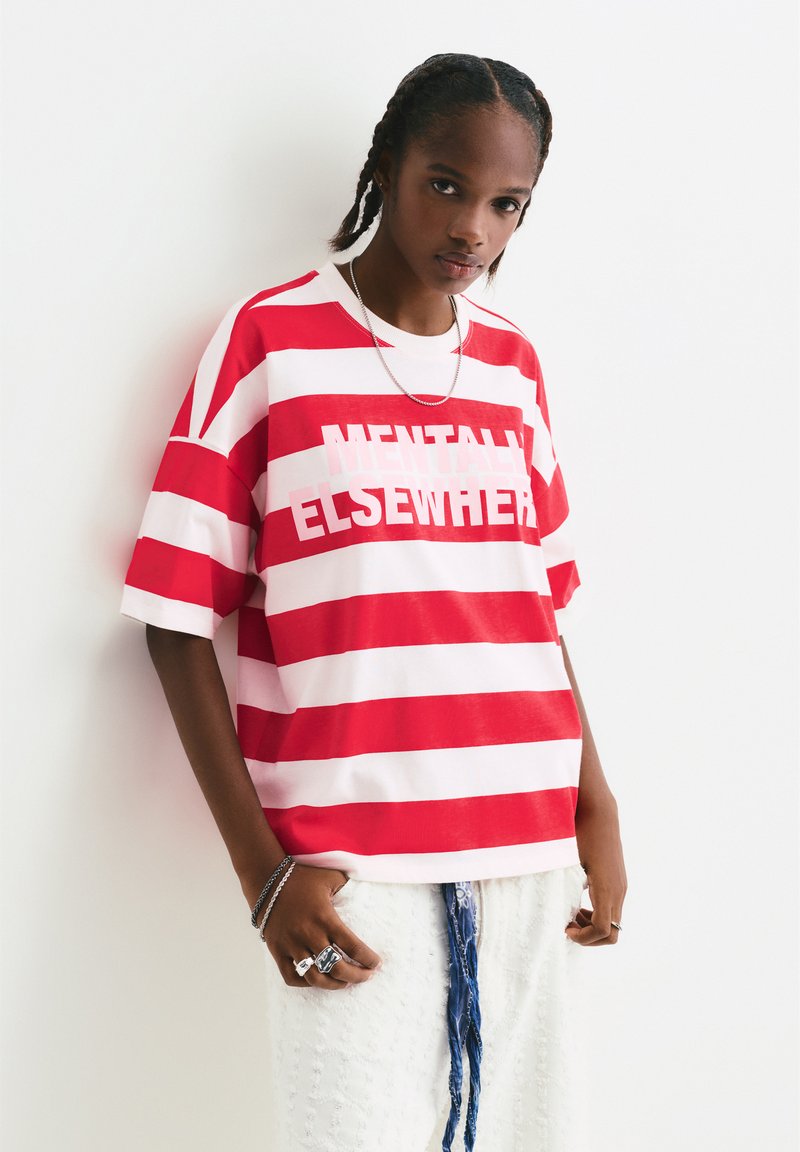Rot-weiße gestreifte Kurzarm-T-Shirt mit dem Schriftzug "MENTALLY ELSEWHERE" in fetten Buchstaben. Weicher Stoff, lockere Passform.