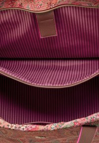 Interieur van een stoffen tas met bloemenpatroon, met maroon en rozenkleurige gestreepte voering, een gladde textuur, ritssluiting en een leren accent.