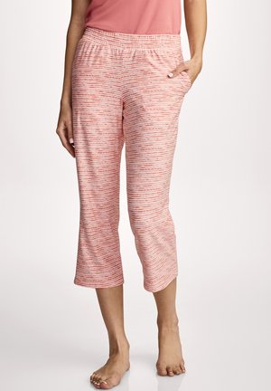 Woman wearing coral and white striped cropped pants with elastic waistband and pockets, barefoot on plain white background.