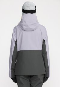 Paarse en donkergrijze skijas met een capuchon, voorzien van een kleurblokkende ontwerpelement. Het materiaal lijkt waterdicht en heeft een gladde textuur.