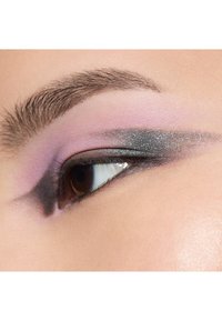 Nærbilde av et øye som viser en gradient øyenskygge med pastell lilla og skimrende grå nyanser, definert eyeliner og naturlige vipper.