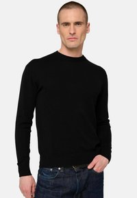 Schwarzer Strickpullover mit rundem Ausschnitt und langen Ärmeln, kombiniert mit blauen Jeans. Besitzt eine weiche Textur und eine standardmäßige Passform.