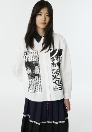 Camisa blanca con características de estampado negro, que incluye una imagen gráfica y texto. La camisa tiene un cuello negro y es de botones.
