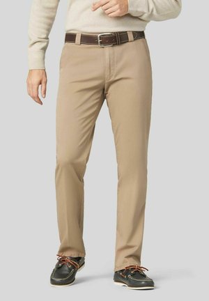 Beige Chinos mit geradem Bein, aus einem Baumwollgemisch gefertigt. Ausgestattet mit einem braunen Gürtel mit einer silbernen Schnalle und akzentuiertem Schuhwerk.