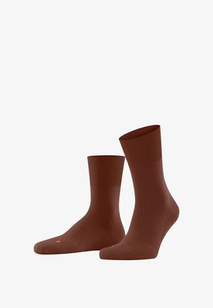 Chaussettes brunes jusqu'aux chevilles en matériau lisse et extensible. Présentent un bord côtelé et un logo discret en orange sur la semelle.