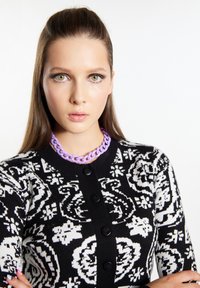 Cardigan in maglia a motivi bianco e nero con bottoni, dotato di una collana a catena viola. Texture liscia e design aderente.