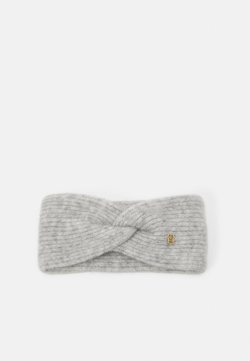 Fascia grigia lavorata a maglia con design attorcigliato. Realizzata in materiale morbido, presenta sottili strisce e un piccolo logo dorato come dettaglio.