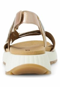 Sandalo con cinturino posteriore in oro rosa e soletta interna beige. Presenta una suola bianca spessa e scanalata. Cinturino in velcro per una vestibilità regolabile.