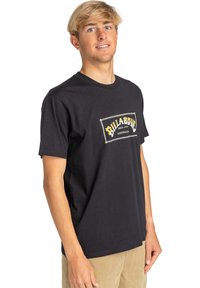Black cotton t-shirt featuring a yellow and white graphic logo with the text "Billabong Australia" on the front. Simple crewneck design.