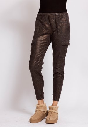 Dark brown textured cargo pants with front pockets and cuffs paired with tan fur-lined ankle boots on a white background.