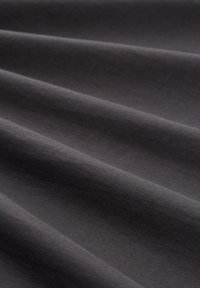 Dunkelgrauer Stoff mit glatter Textur, der subtile Wellen und Falten zeigt und ein schlichtes Design ohne Muster oder Verzierungen aufweist.