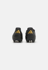Black soccer cleats with a textured surface, featuring gold Adidas logo accents on the heel and rubber studs for traction.