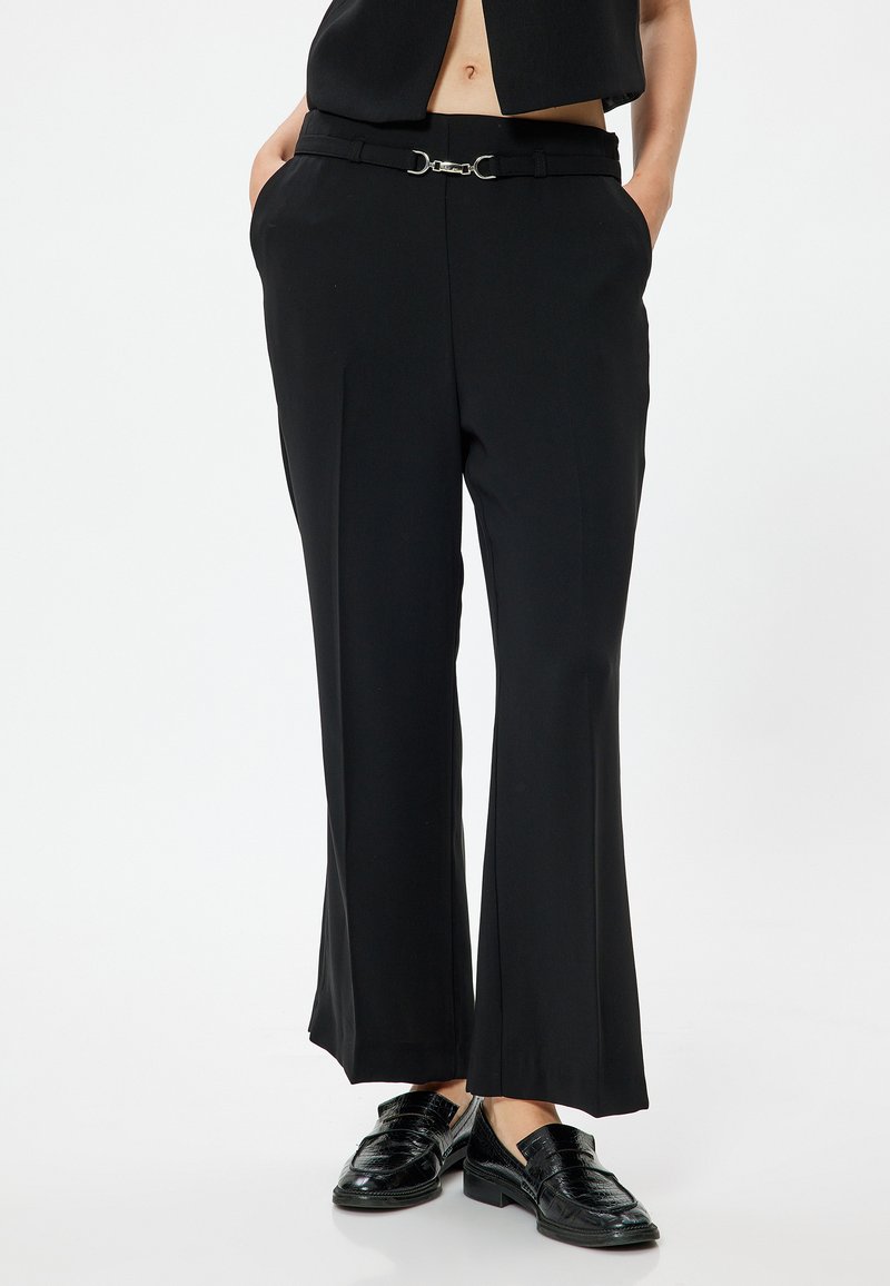 Svart skräddarsydda byxor med rak benprofil, med en silverfärgad bältesknopp och fickor. Tillverkade av ett mjukt och lätt tyg.