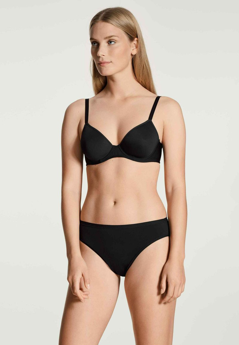 Black bra with soft cups, adjustable straps, and a horizontal seam. Paired with matching black brief featuring a standard waistband.