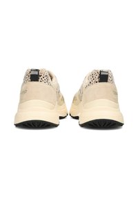 Zapatillas beige con un upper texturizado, acentos negros y una suela acolchada; vista trasera que muestra un acabado suave y elementos contrastantes.