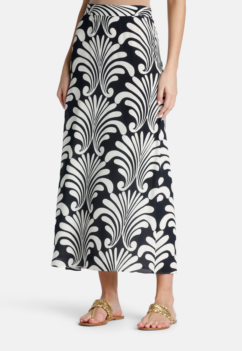 Maxi rok in marineblauw met witte bloemmotieven, met een hoge taille en een vloeiende stijl, gecombineerd met beige gevlochten sandalen.