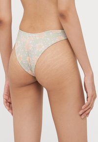 Květinové spodní část bikiny v zelenej farbe s bledooranžovými a svetlofialovými kvetmi. Má nízky strih a hladkú textúru látky.
