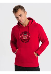 Rode hoodie van zachte stof, met een buidelzak en een capuchon met trekkoord. Gecentreerde grafische print in het zwart met circulaire tekstdetails.