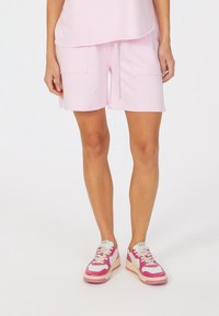 Pink cotton shorts with two front pockets, elastic waistband, and drawstring. Paired with pink and white sneakers.