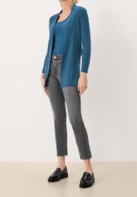 Tealfärgad ribbad cardigan med öppen frontdesign, matchad med en tank top, grå smal-tighta jeans och svarta loafers. Slät textur överlag.