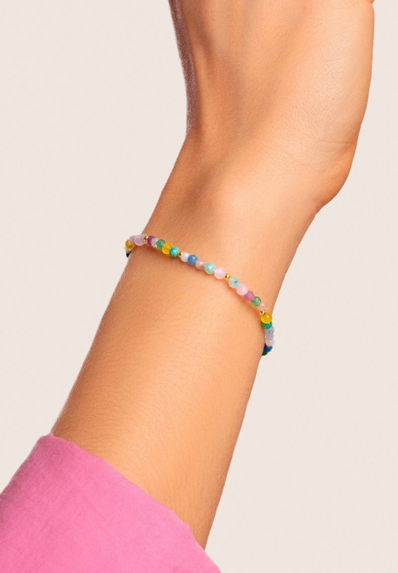 Pulsera de cuentas con una variedad de cuentas coloridas (rosa, verde, azul, amarillo) con pequeños acentos dorados, llevada en una mano con un diseño sin adornos.