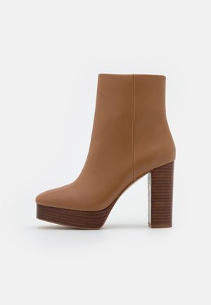 Botte cheville en cuir marron avec un bout arrondi, un talon en bois épais et une base plateforme, présentant une texture lisse et des lignes épurées.