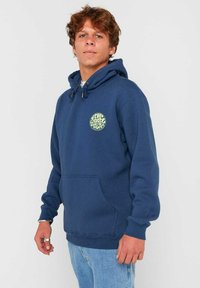 Felpa con cappuccio blu navy in misto cotone, dotata di una tasca frontale a marsupio e un logo circolare di colore verde chiaro sul petto.