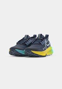 Scarpe sportive con tomaia blu navy, suola con gradiente azzurro e giallo, caratterizzate da mesh testurizzato, lacci prominenti e dettagli del logo.