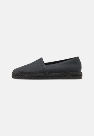 Espadrille noire à enfiler avec tissu texturé, bout rond et semelle en jute tressé. Design minimaliste sans matériel visible.