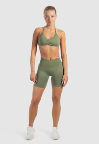 Olivgrünes Sportset mit einem Bandeau-Top mit gerafftem Detail und hoch taillierten Shorts. Weicher, dehnbarer Stoff mit glatter Textur.