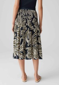 Gonna midi a campana con sfondo nero, caratterizzata da grandi motivi a foglia beige. Vita elastica, tessuto texturizzato e vestibilità comoda.