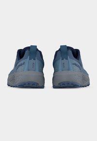 Ζευγάρι μπλε παπουτσιών για τρέξιμο σε μονοπάτια, με τις επιγραφές "ALTRA" και "GTR" στις ταμπελίτσες της φτέρνας, εμφανιζόμενα από πίσω.