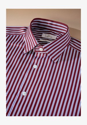 Piros és fehér csíkos, slim-fit ing, gombos gallérral, fehér gombokkal és sima textúrájú anyaggal. Címke látható a gallér belsejében.