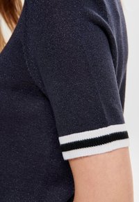 Námořnický pletený top s krátkým rukávem, s bílým a černým pruhovaným žebrovaným manžetem. Texturovaná látka s jemným leskem.