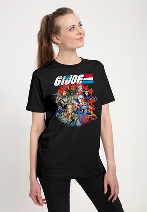 T-shirt in cotone nero con una grafica colorata di G.I. Joe che presenta diversi personaggi, scritte in grassetto e un design con stelle e strisce.